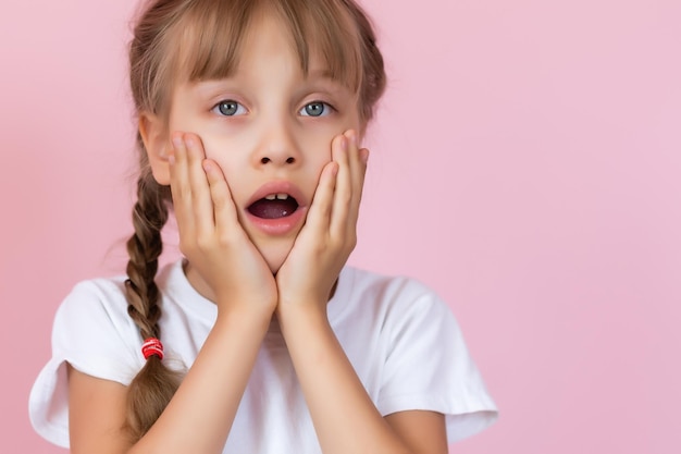 Niña linda que cubre su boca mostrando una intensa expresión de miedo y terror, aislada