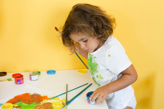 Foto niña linda que dibuja con pinturas de colores