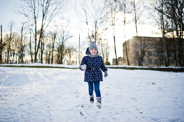 Niña linda que se divierte al aire libre en día de invierno.