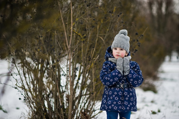 Niña linda que se divierte al aire libre en día de invierno.