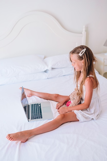 Niña linda que hace la tarea en la computadora portátil