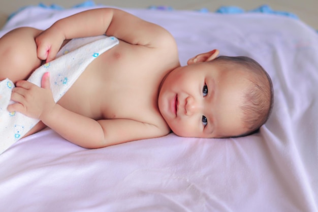 Una niña linda que mira hacia otro lado mientras está acostada en la cama en casa.