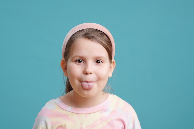 Niña linda que muestra la lengua mientras mira a la cámara