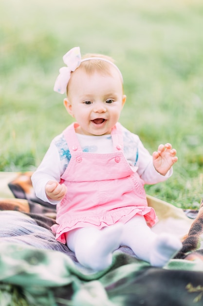 Niña linda que se sienta en la hierba en un día soleado