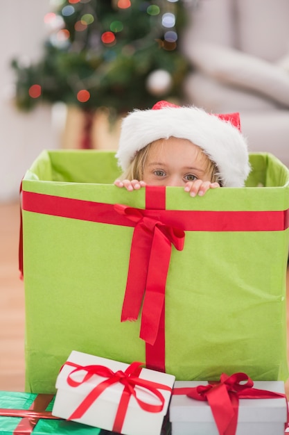 Niña linda que se sienta en regalo gigante de la Navidad