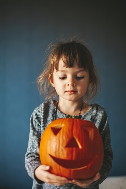 Niña linda que sostiene una calabaza de Halloween