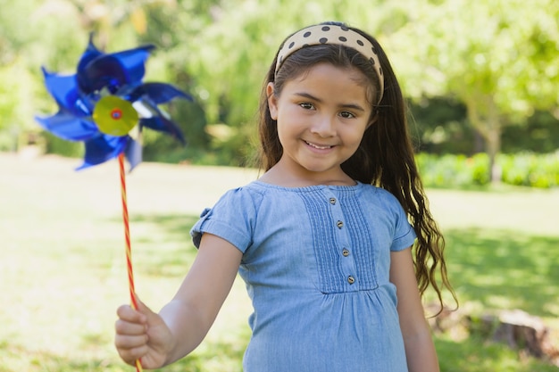 Niña linda que sostiene el molinillo de viento en el parque