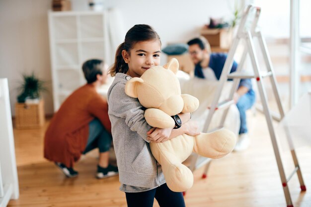 Niña linda que sostiene un oso de peluche en su nuevo hogar