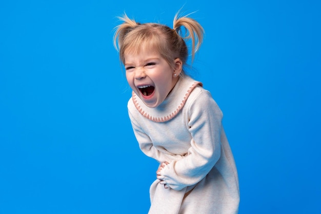 Niña linda que sufre de dolor de estómago en el fondo azul