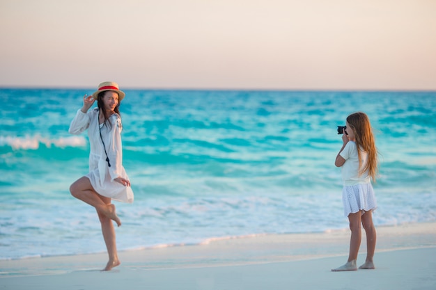 Niña linda que toma la foto de su madre en la playa tropical