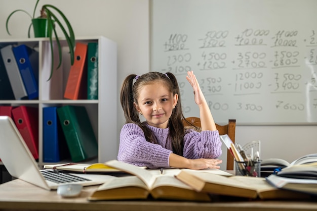 Niña linda que usa una computadora portátil para estudiar en línea en casa