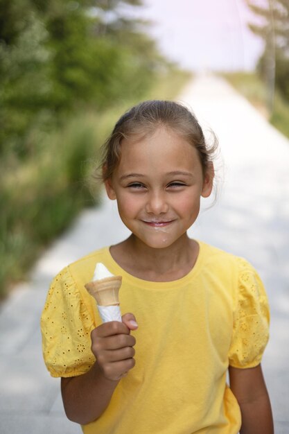 Niña linda riendo niña pequeña come helado en un día caluroso helado en un cono de gofres