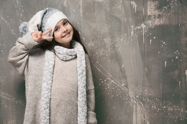 Niña linda en ropa de abrigo sobre fondo grunge