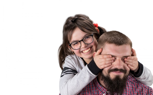 Niña linda en ropa casual que cubre los ojos de su padre