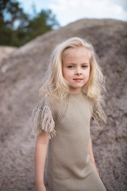 Niña linda en ropa elegante sobre un fondo de rocas