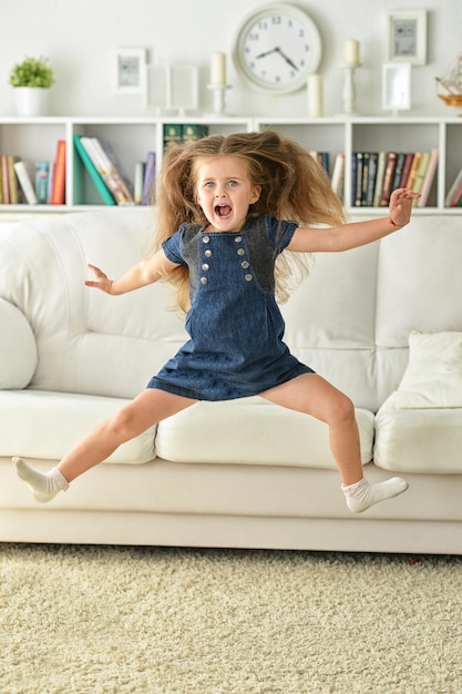 Niña linda saltando sobre la alfombra