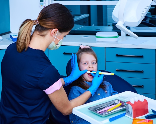 Niña linda sentada en la oficina de dentistas