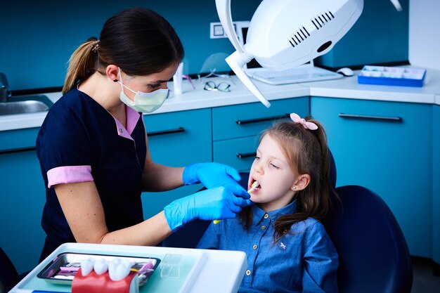 Niña linda sentada en la oficina de dentistas