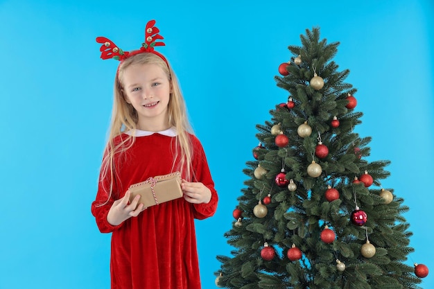 Niña linda sobre fondo azul con árbol de Navidad