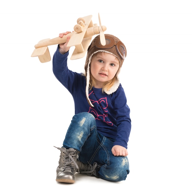 Niña linda en sombrero piloto con avión de madera