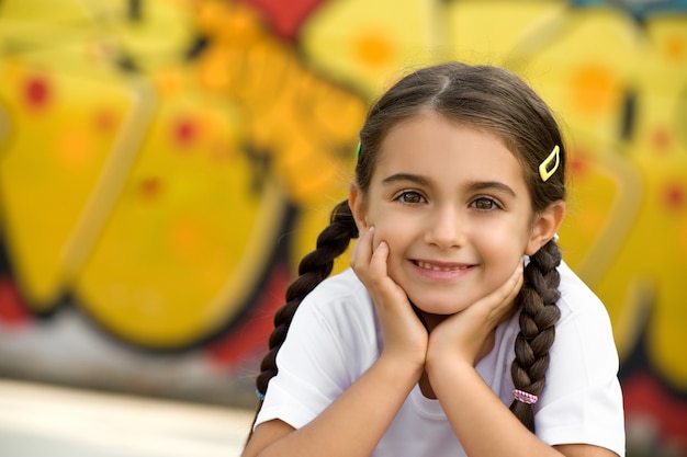 Niña linda sonriente con las manos en la cara