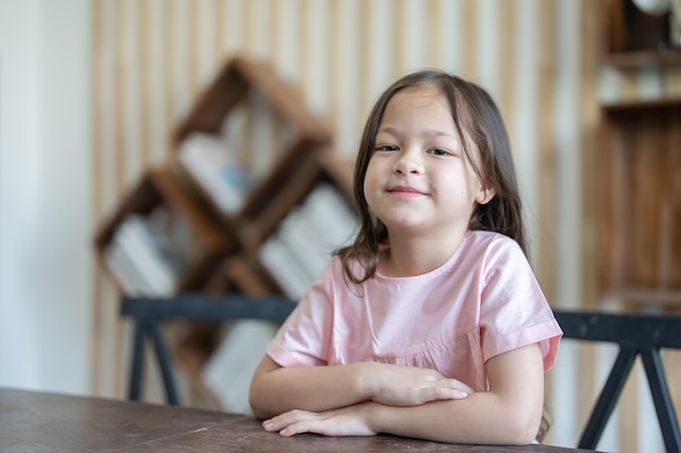 Niña linda sonriente sentada en el escritorio en el aula de la escuela primaria