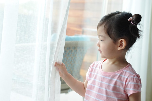 Foto una niña linda sostiene la cortina blanca con espacio para copiar