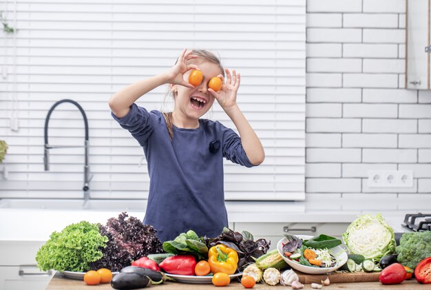 Una niña linda sostiene verduras frescas mientras prepara un espacio de copia de ensalada.