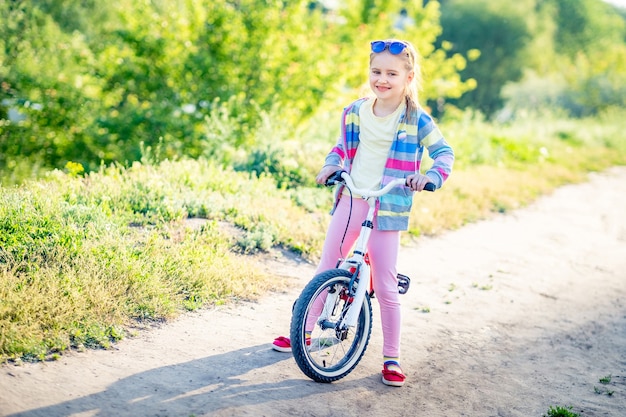 Foto niña linda con su bicicleta en el camino