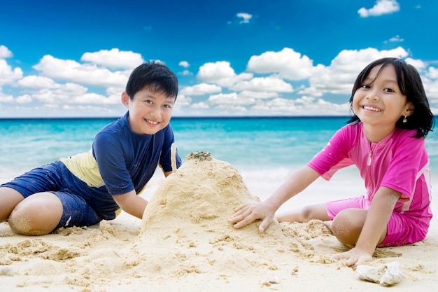 Una niña linda con su hermano jugando a la arena.