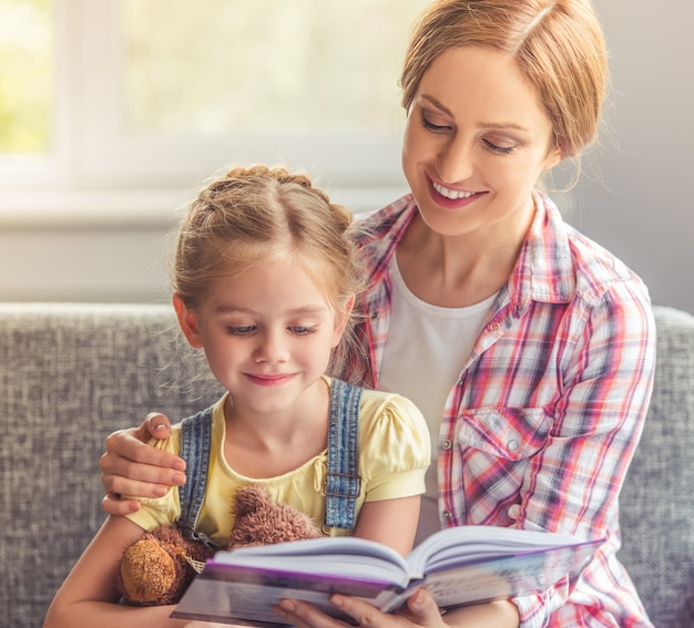 Niña linda y su hermosa madre están leyendo el libro.