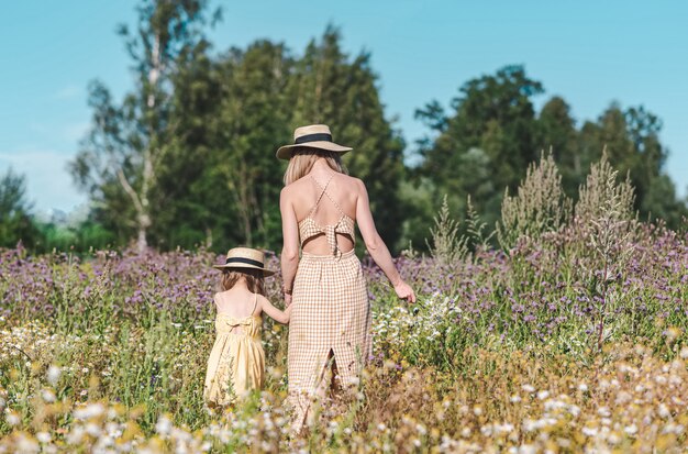 Niña linda con su madre caminando en el campo de flores