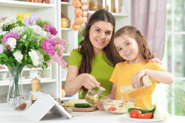 Niña linda con su madre cocinando juntos