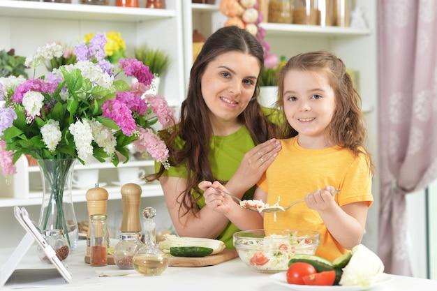 Niña linda con su madre cocinando juntos