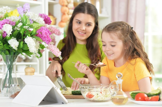 Niña linda con su madre cocinando juntos