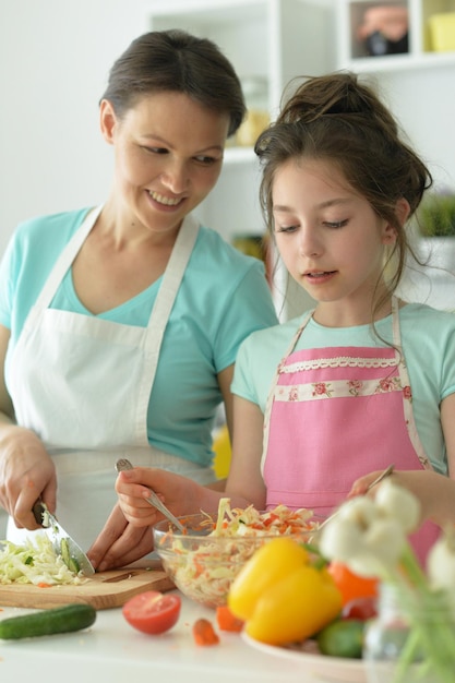 Niña linda con su madre cocinando juntos