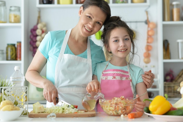 Niña linda con su madre cocinando juntos
