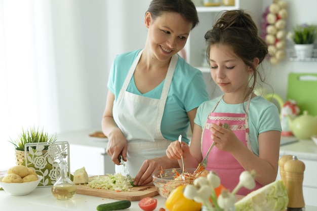 Niña linda con su madre cocinando juntos