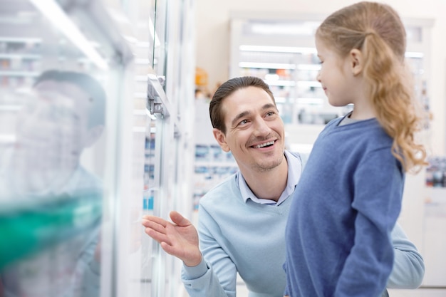 Niña linda con su padre en una farmacia