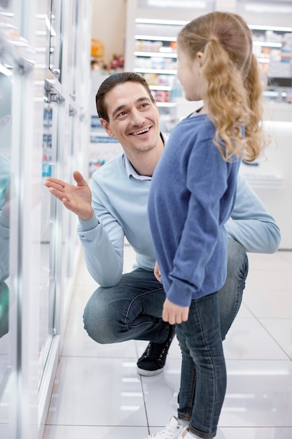 Niña linda con su padre en una farmacia