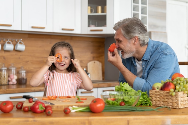 Niña linda y su papá guapo se divierten mientras cocinan en la cocina de casa.