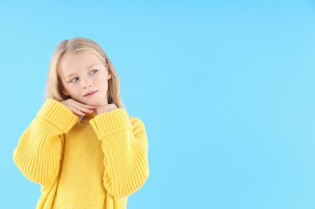 Niña linda en suéter sobre fondo azul