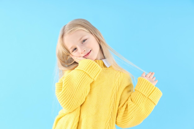 Niña linda en suéter sobre fondo azul