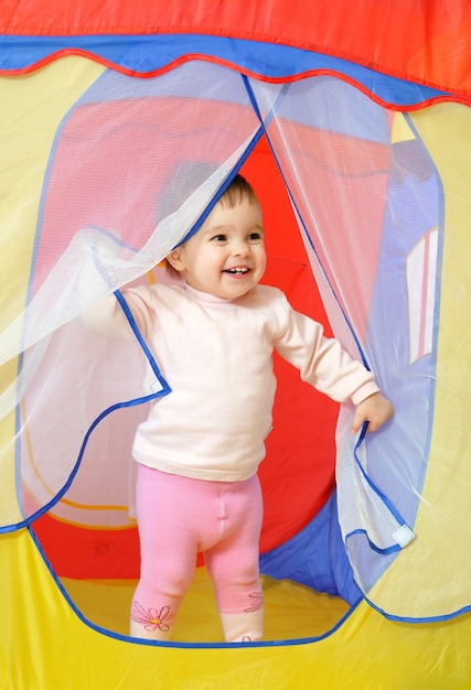 Niña linda tiene juguete en las manos en casita