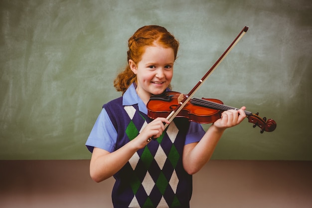 Foto niña linda tocando el violín en el aula