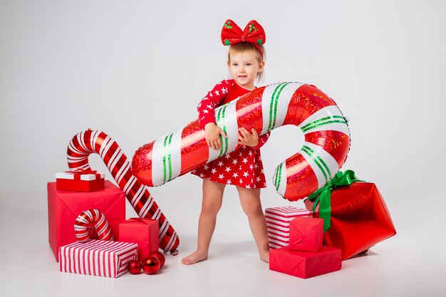 Niña linda en un traje festivo con regalos de Navidad