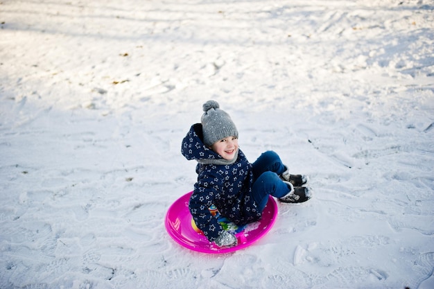 Niña linda con trineos de platillo al aire libre en día de invierno