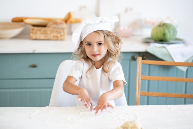 Niña linda con uniforme de chef en la cocina