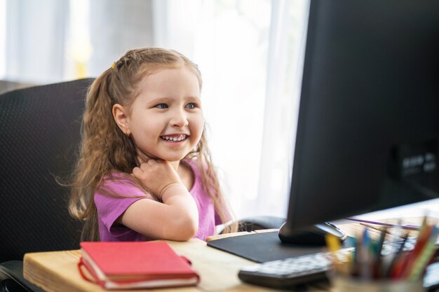 Una niña linda usando una computadora para e-learning remoto.