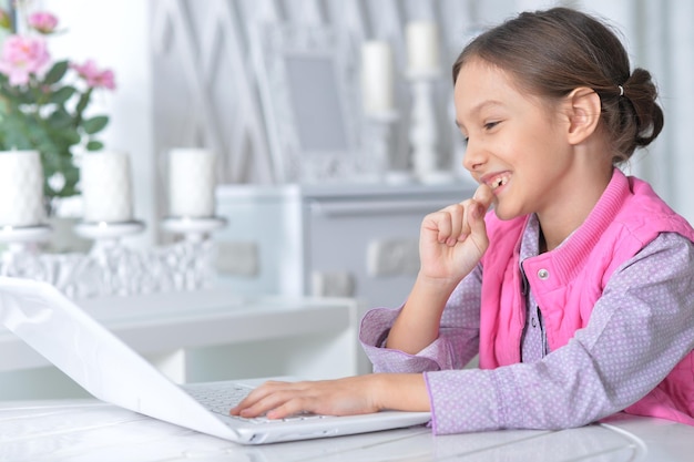 Una niña linda usando una computadora portátil moderna